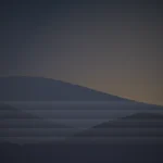 タイ北部の山あいに夕暮れが落ちる情景。長期滞在先での生活を思う場面
