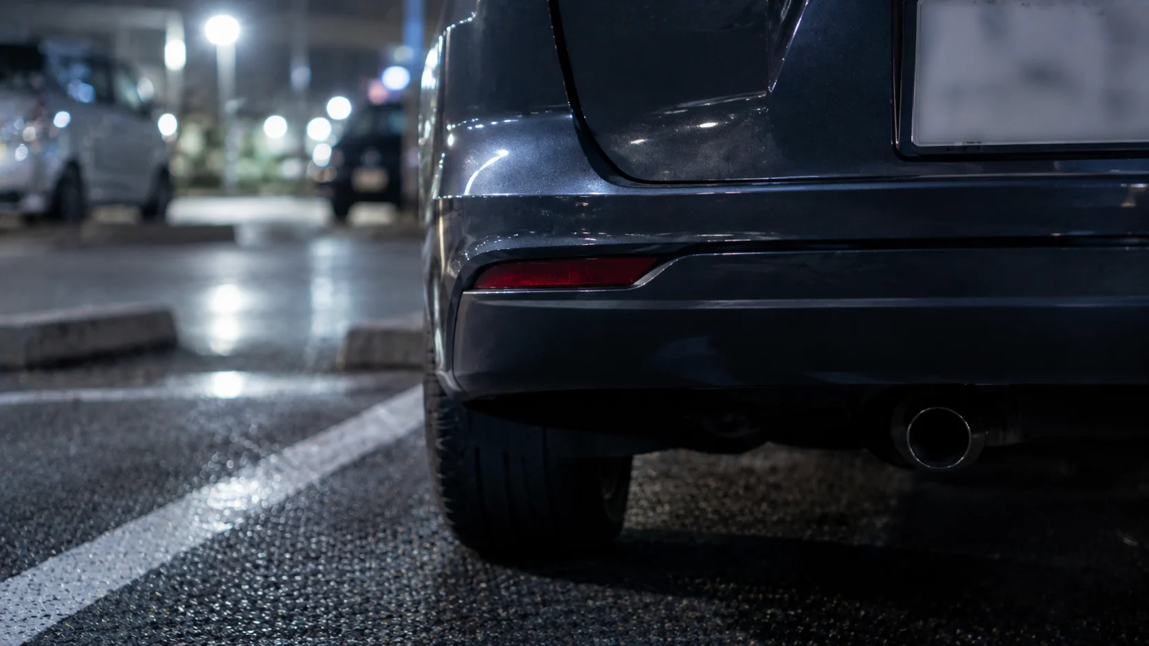 夜の駐車場に停まった車のリアバンパー付近