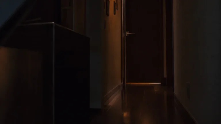 夜の日本の住宅で閉じた子ども部屋のドアと、その手前の暗い通路、ドアの下から漏れる明かり
